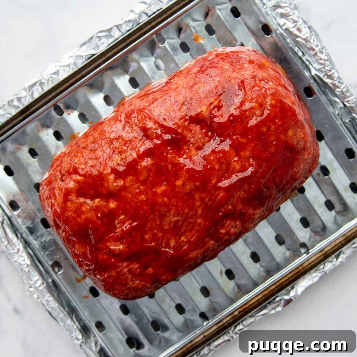Juicy Gluten-Free Meatloaf: A Taste of Home Comfort 5 A raw meatloaf, glistening with a fresh coat of its signature ketchup glaze, poised to be baked to perfection.