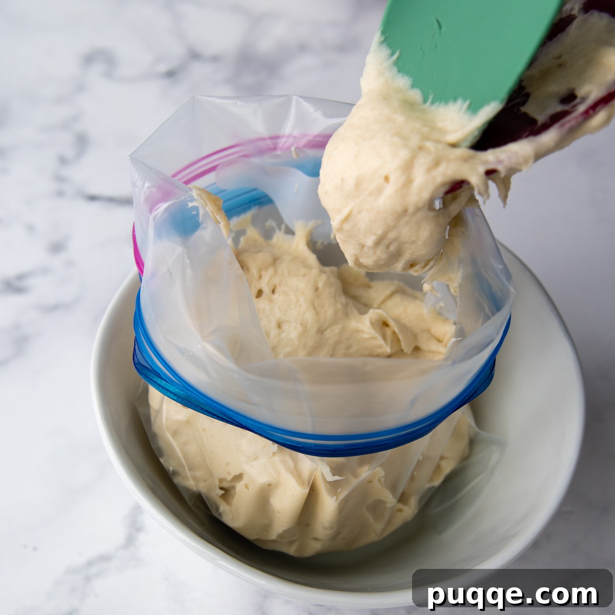 Scooping gluten-free breadstick dough into a Ziploc bag for easy piping.