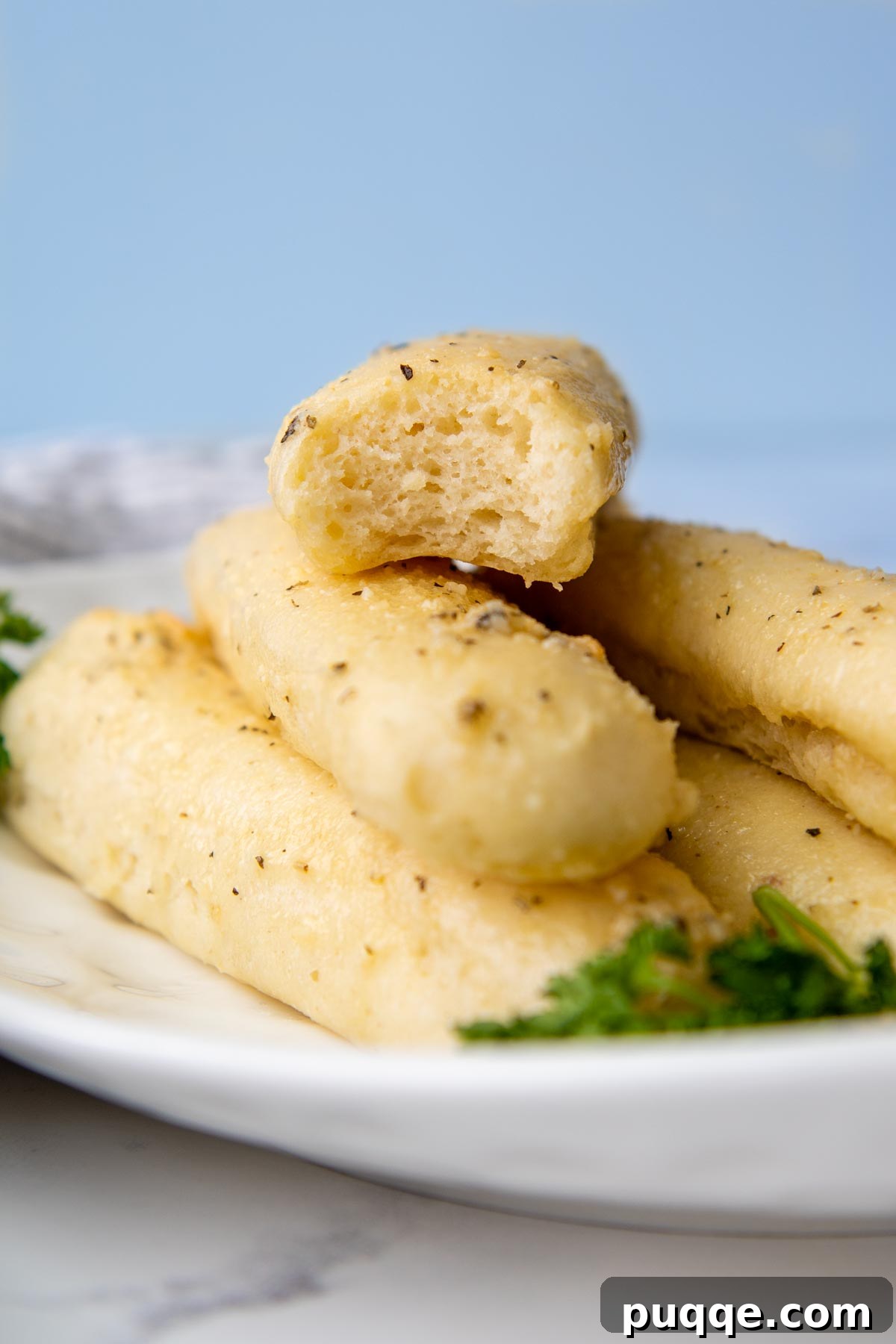 A close-up shot of a perfect gluten-free breadstick with a bite taken out, showing its soft interior.