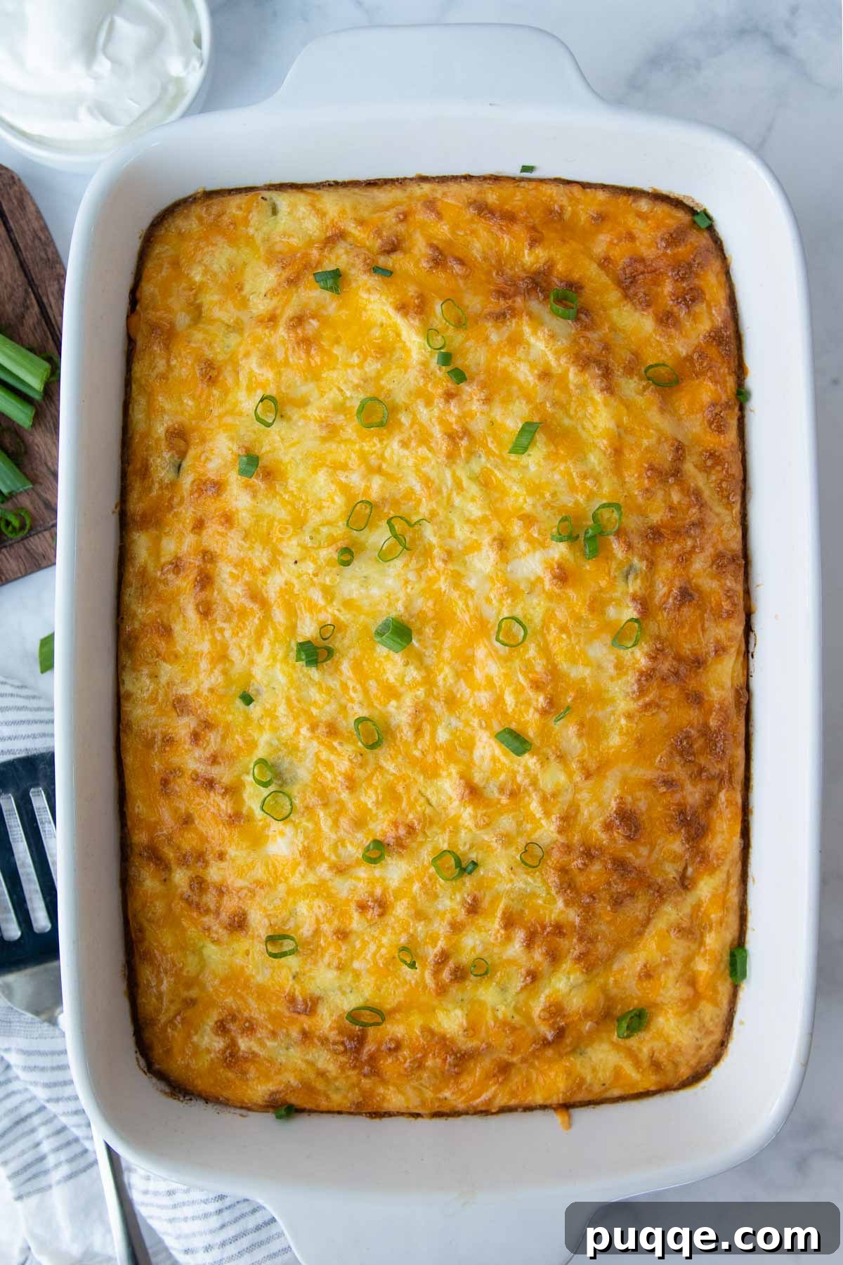 A beautifully baked egg casserole with vibrant green onions sprinkled on top, ready to be served.