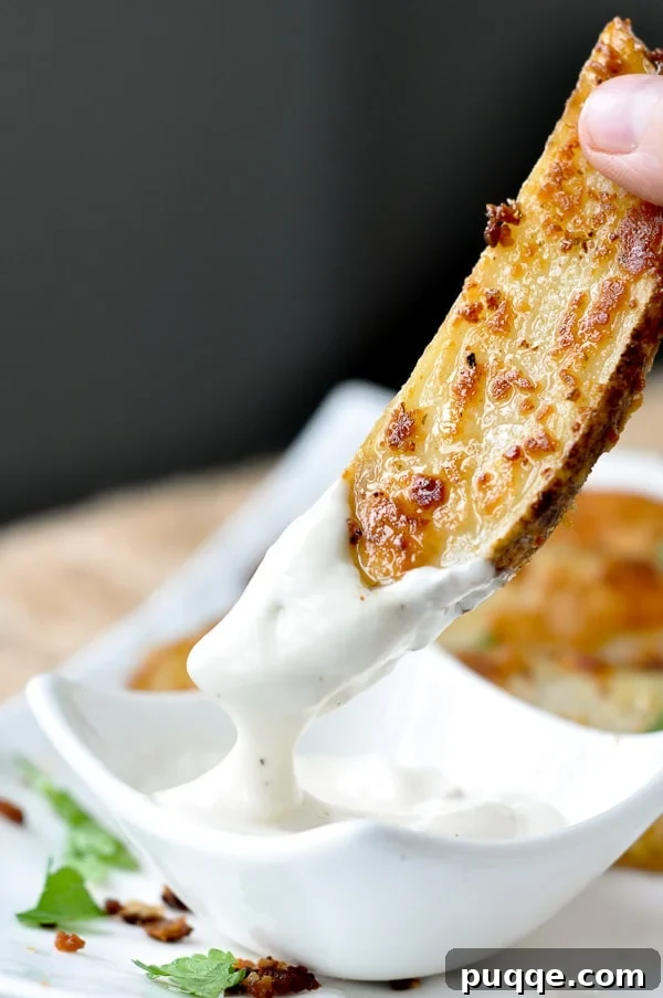 A roasted ranch potato being dipped into creamy ranch dressing, highlighting its golden crisp exterior.