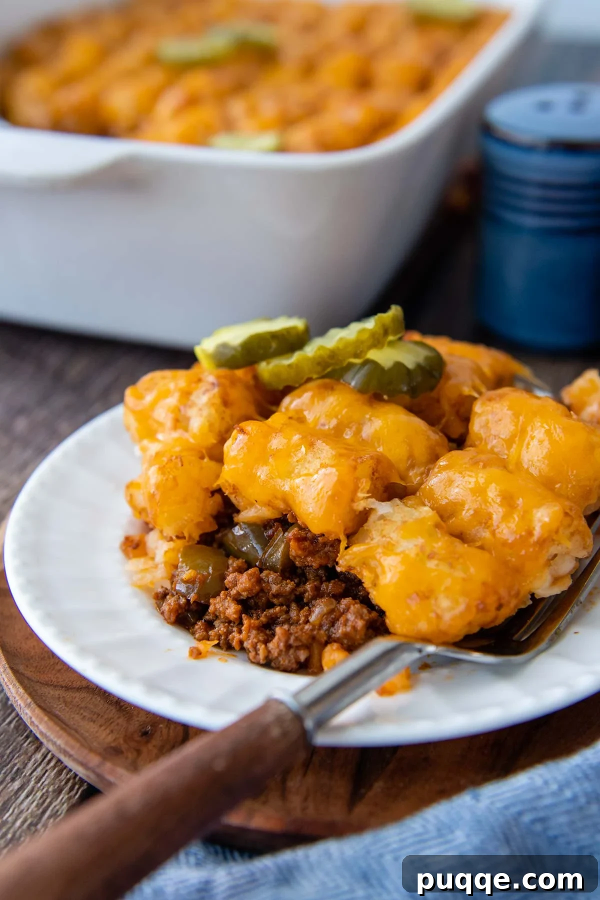 Golden Tater Tot Sloppy Joe Bake 2 A generous serving of homemade Sloppy Joe Tater Tot Casserole on a white plate, with a fork resting beside it, highlighting the golden tater tots, melted cheddar, and rich meat sauce.