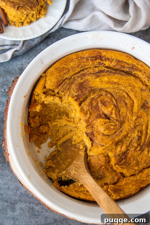 An overhead shot of a sweet potato spoon bread casserole with a scoop taken out, revealing its soft texture.