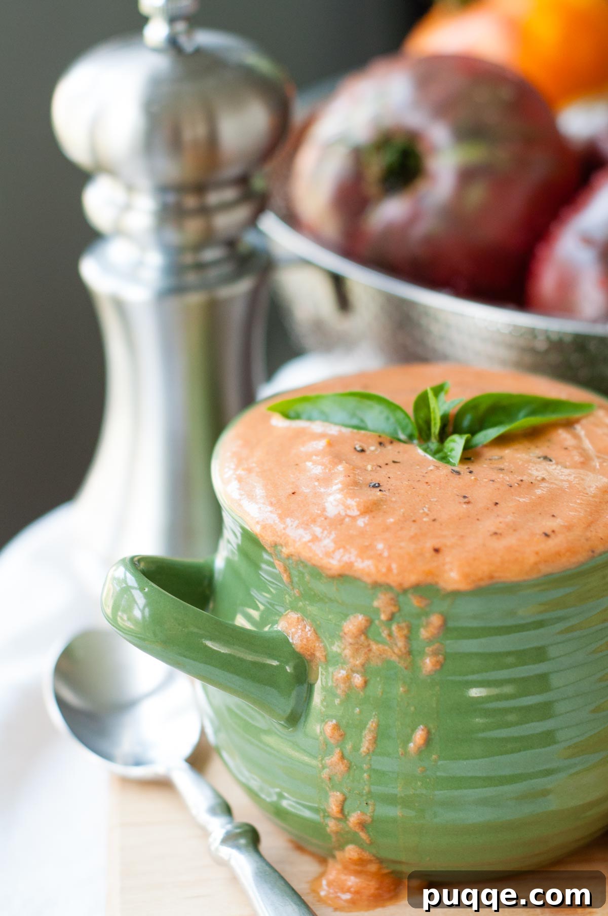 A warm bowl of creamy roasted tomato soup, garnished with fresh basil leaves.