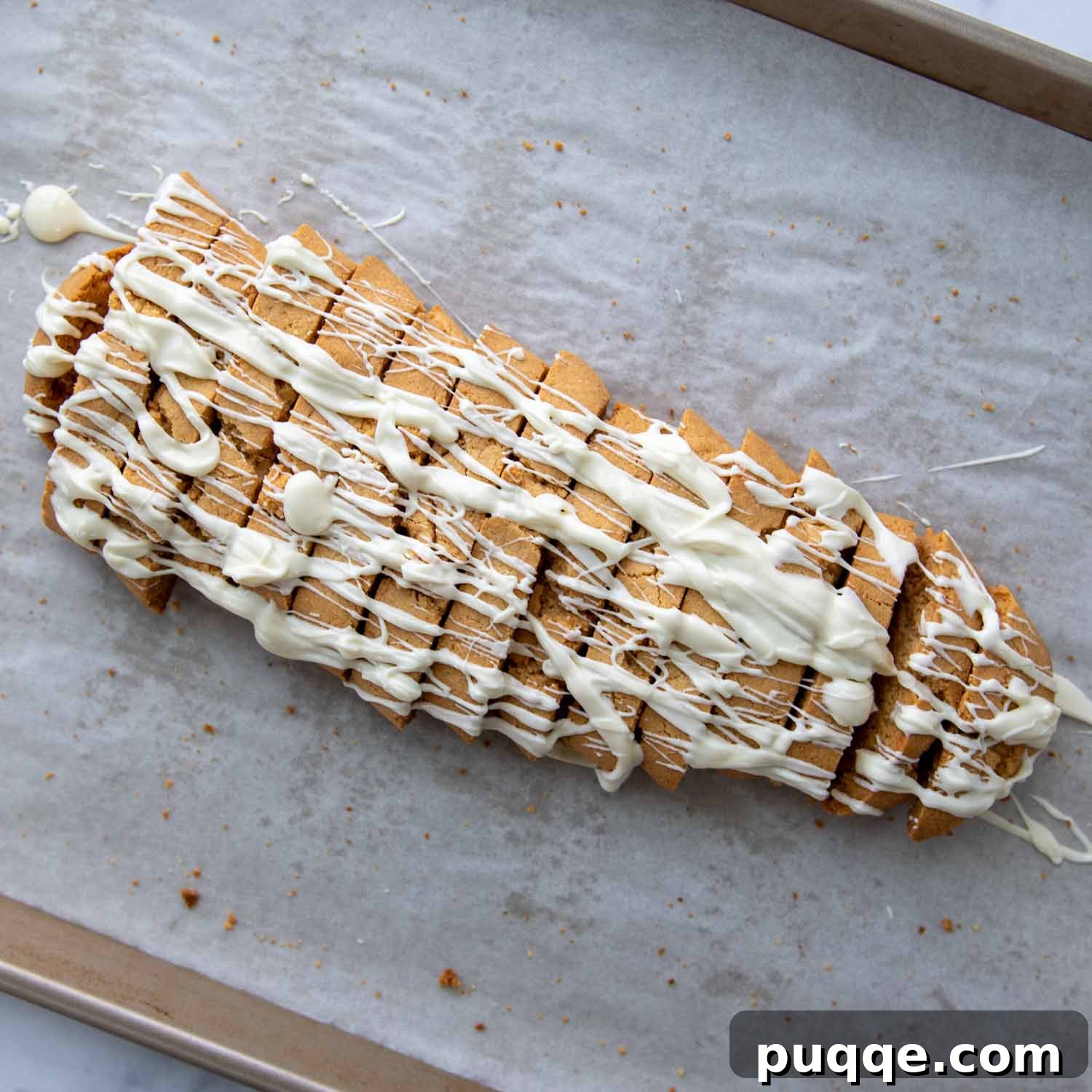 Artful white chocolate drizzle over golden-brown almond flour biscotti, creating an appealing finish.