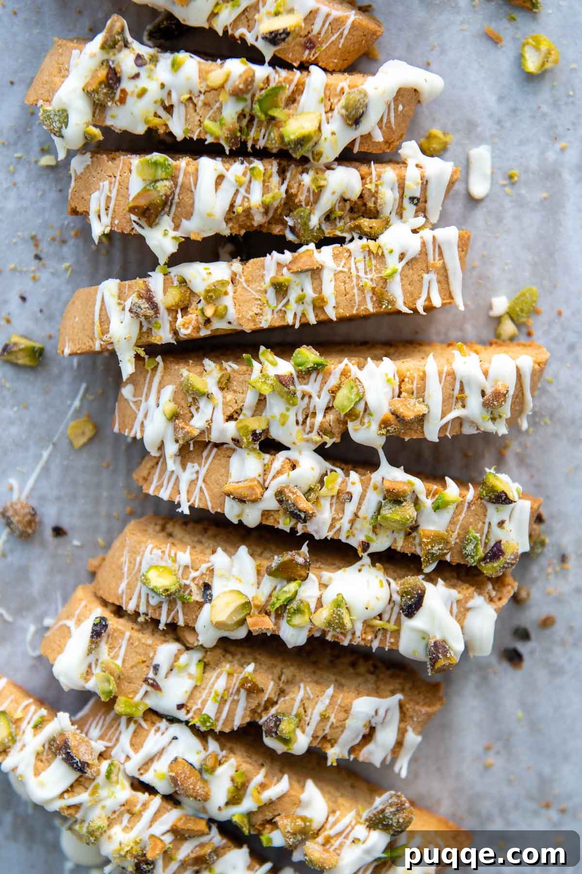 An overhead shot showcasing beautifully drizzled almond flour biscotti with white chocolate and green pistachios.