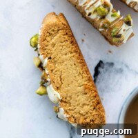 A face-up slice of almond flour biscotti with a steaming cup of coffee in the background.