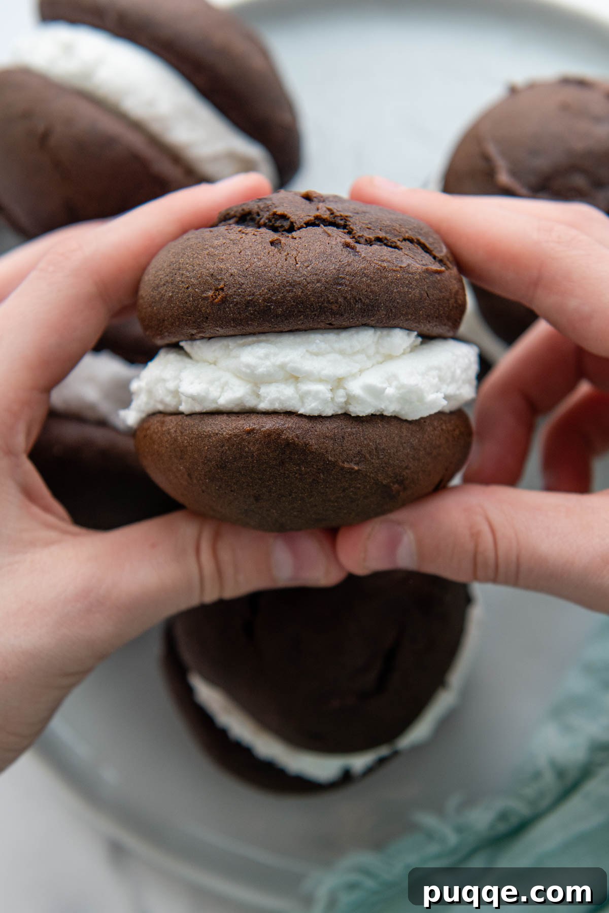 Grandma's Easy Gluten-Free Whoopie Pies 2 Hands holding a perfectly assembled gluten-free whoopie pie, showcasing the rich chocolate cake and fluffy white filling.