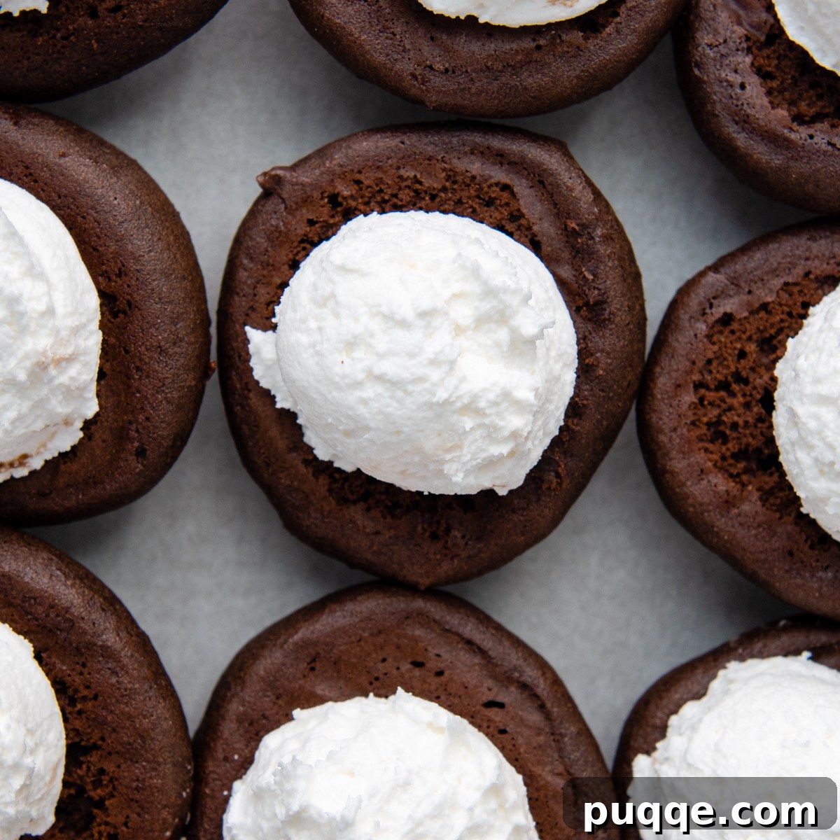 Grandma's Easy Gluten-Free Whoopie Pies 7 The bottom halves of several chocolate whoopie pie cookies generously filled with fluffy white vanilla cream, ready to be topped.