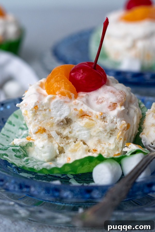 A cup of creamy frozen fruit salad, with a spoonful removed, resting on a blue plate, offering a refreshing dessert option.