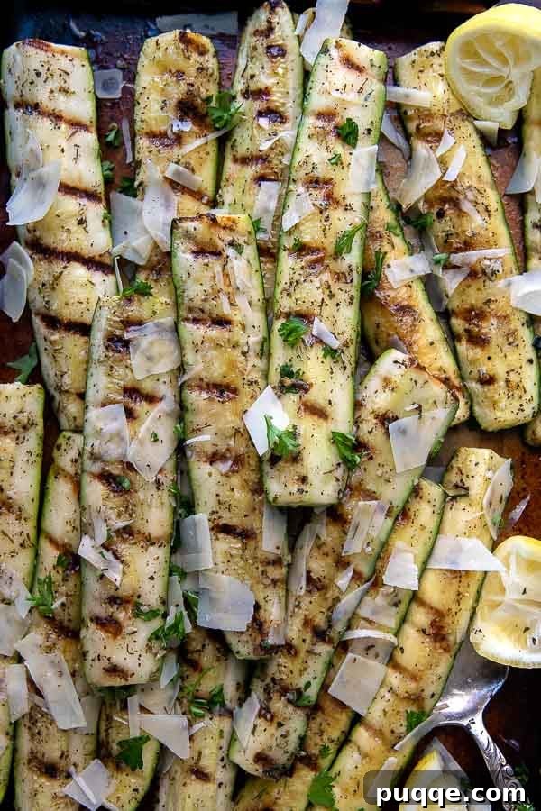 An overhead shot featuring perfectly grilled zucchini and squash slices arranged on a sheet pan, with serving tongs nearby.