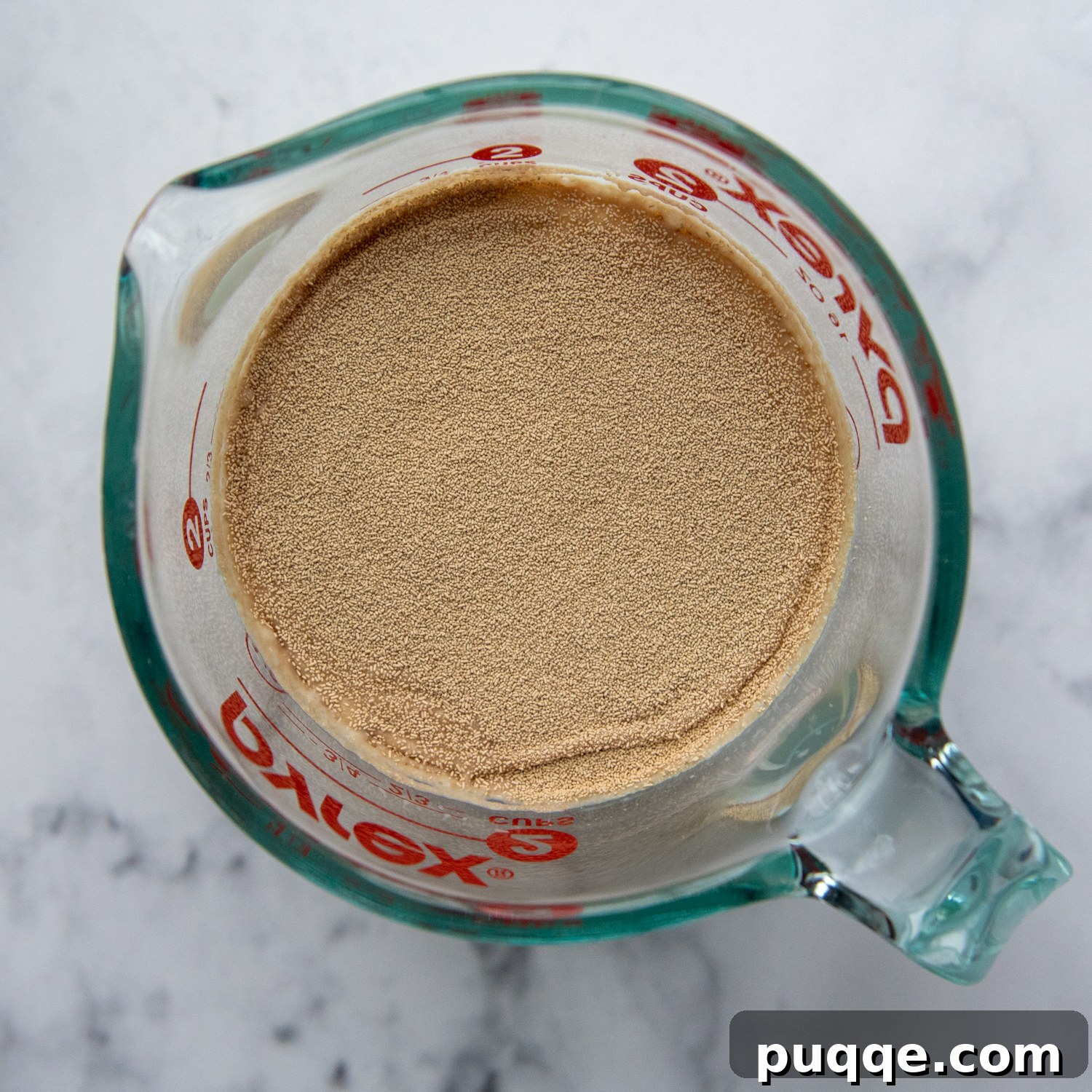 Fluffy Gluten-Free Italian Focaccia Made Easy 3 Active dry yeast being activated in a measuring cup with warm water and milk, showing a light foam forming on the surface.