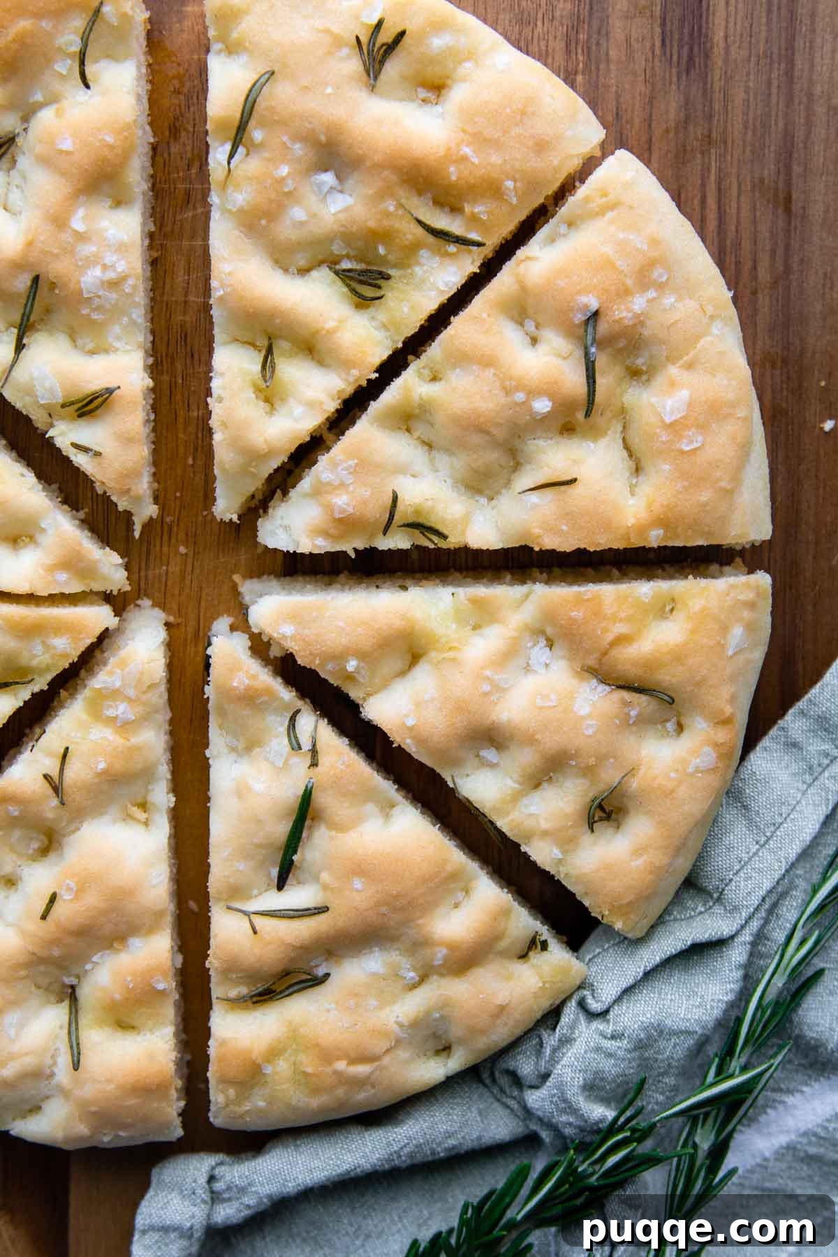 Fluffy Gluten-Free Italian Focaccia Made Easy 6 Freshly baked focaccia, sliced into wedges, arranged artfully on a rustic wood cutting board, garnished with fresh rosemary.