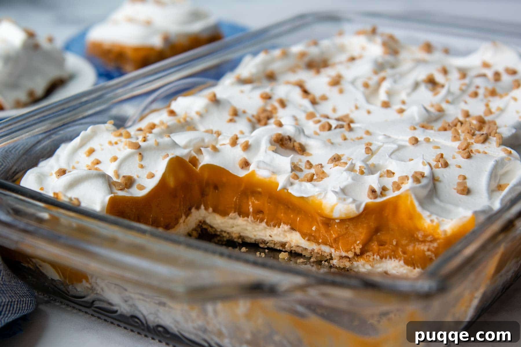 A glass baking dish filled with layered butterscotch dessert, with several slices already removed.