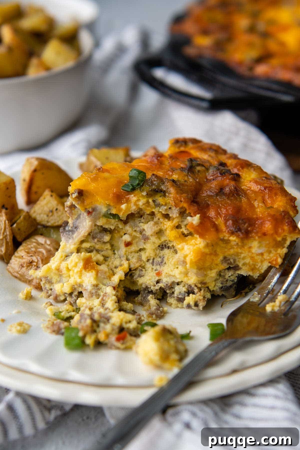 A slice of the freshly baked crustless quiche on a white plate with a fork resting next to it, showing the delicious filling.