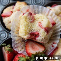 Light and Fluffy Gluten-Free Strawberry Muffins 7 a bitten muffins facing up towards the camera resting on a paper liner.