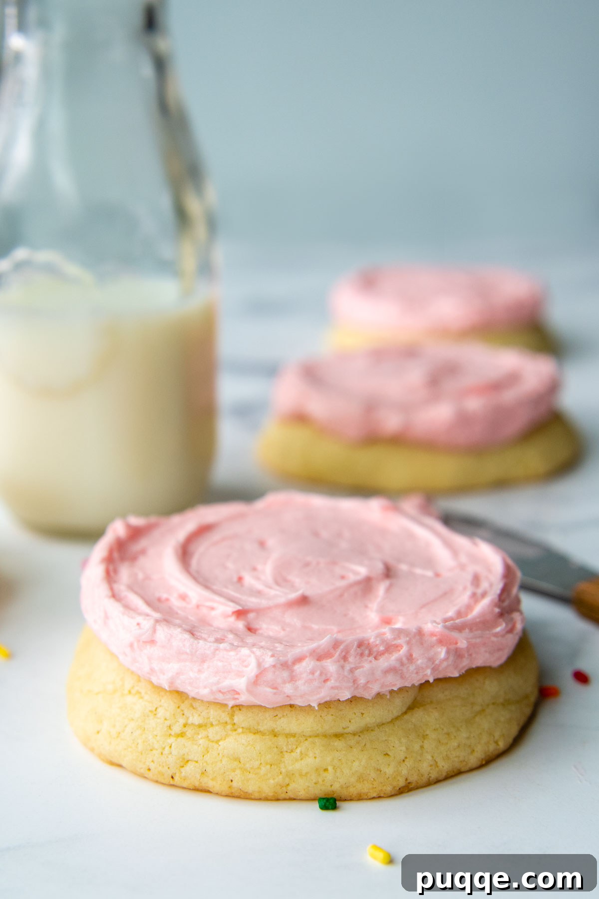 Ultimate Gluten-Free Crumbl Cookies 7 A close-up, straight-on shot of a perfectly frosted sugar cookie with pink buttercream, highlighting its soft texture.