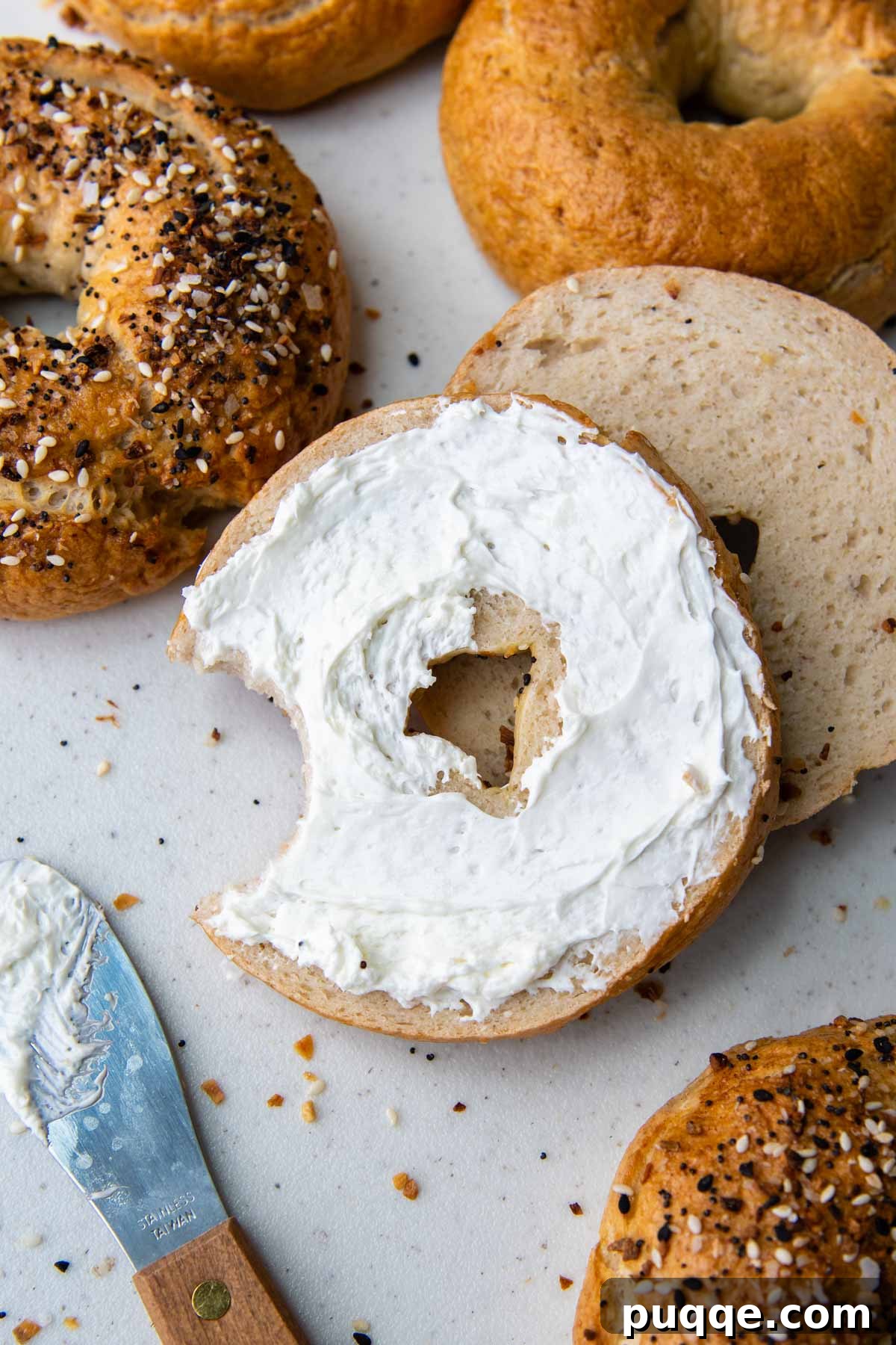 Effortless Soft & Chewy Gluten-Free Bagels 7 A delicious gluten-free bagel topped with cream cheese, with a bite taken out, inviting you to enjoy its fresh taste.