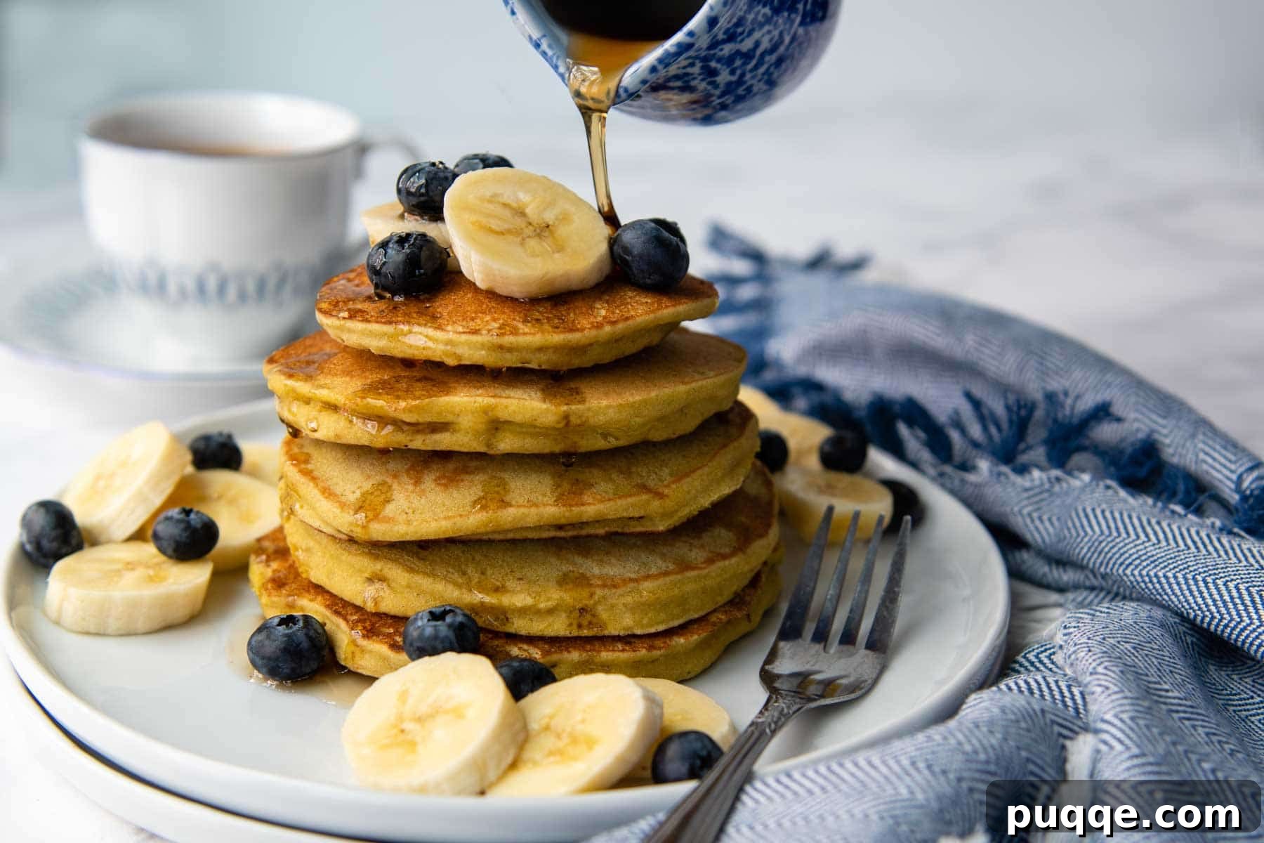 Delicious Gluten-Free Banana Buckwheat Pancakes 5 a small blue carafe pouring syrup on top of the pancakes.