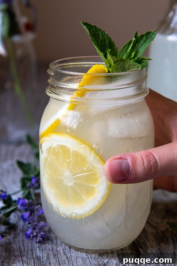 a hand picking up a glass jar or vodka and lemonade