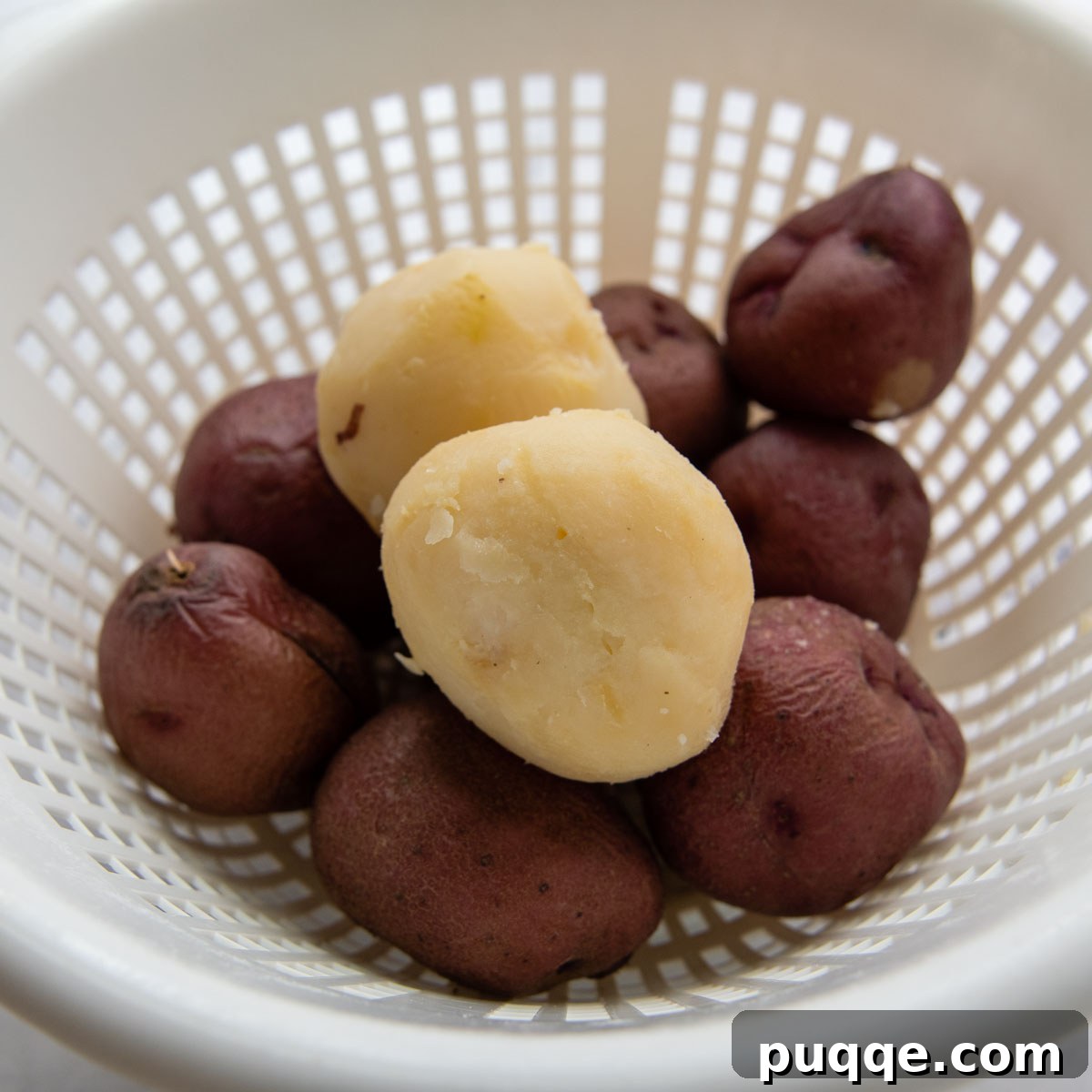 Wholesome Gluten-Free Amish Potato Salad 4 boiled potatoes in a colander with one peeled.