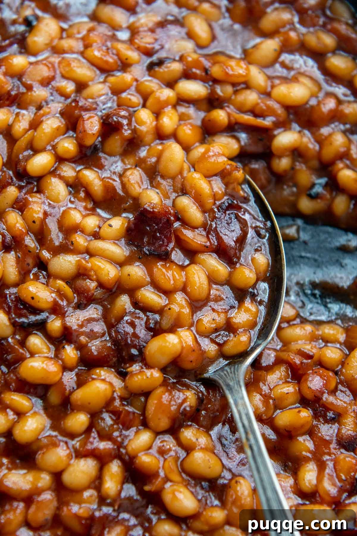 Ultimate Gluten Free Baked Beans 2 A close-up of an antique spoon scooping delicious gluten-free baked beans, showcasing their rich texture and deep color.