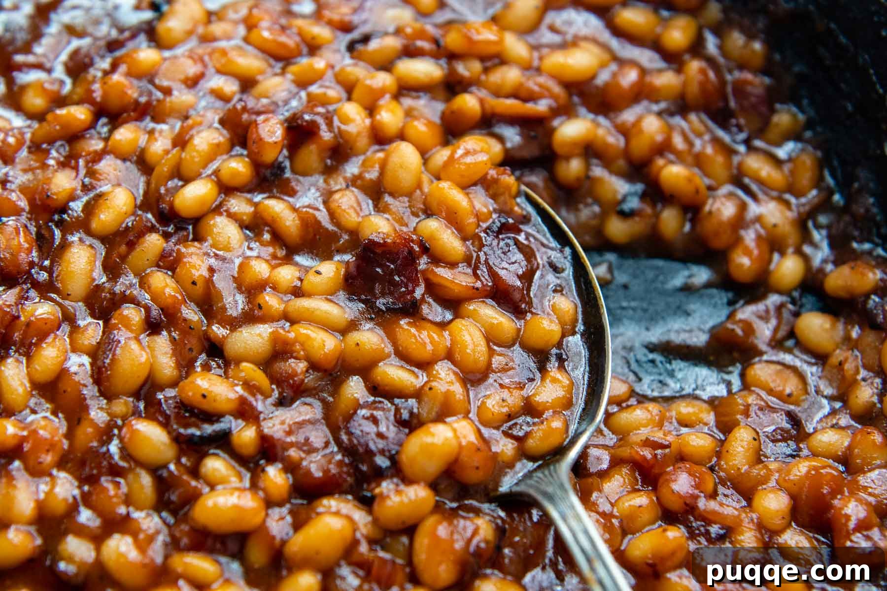 Ultimate Gluten Free Baked Beans 7 Another enticing image of a spoon lifting up a generous portion of gluten-free baked beans, highlighting their thick, glossy sauce.