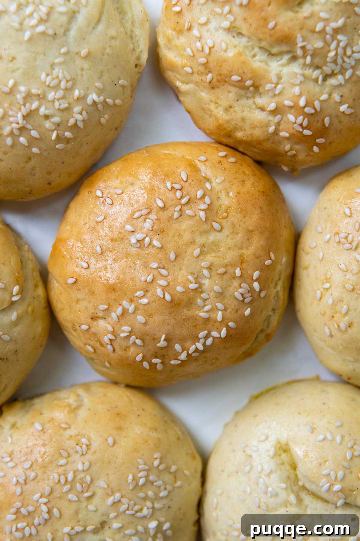 Unbelievably Soft Gluten Free Hamburger Buns No Crumbs 3 An inviting overhead shot of perfectly baked golden-brown gluten-free burger buns cooling on a white background.
