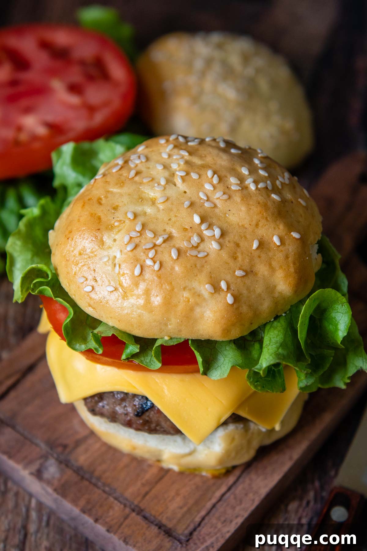 Unbelievably Soft Gluten Free Hamburger Buns No Crumbs 8 A mouth-watering burger with fresh lettuce, ripe tomato, and melted cheese, served on a homemade gluten-free bun atop a rustic wood cutting board.