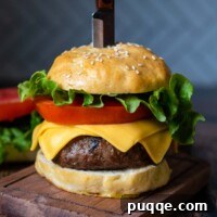 A straight-on shot of an assembled burger with a knife stabbed into the top, showcasing the soft gluten-free bun.