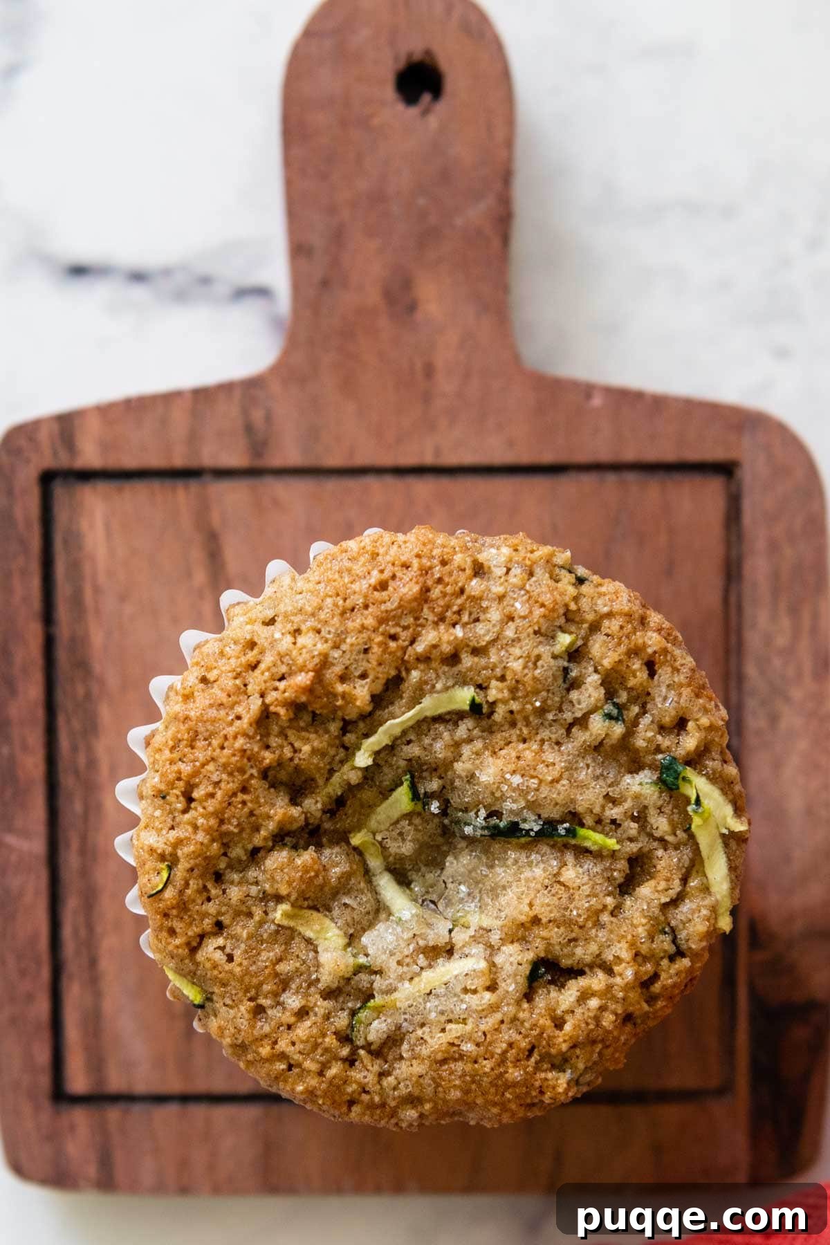 An overhead shot of freshly baked almond flour zucchini muffins arranged on a rustic wood cutting board.