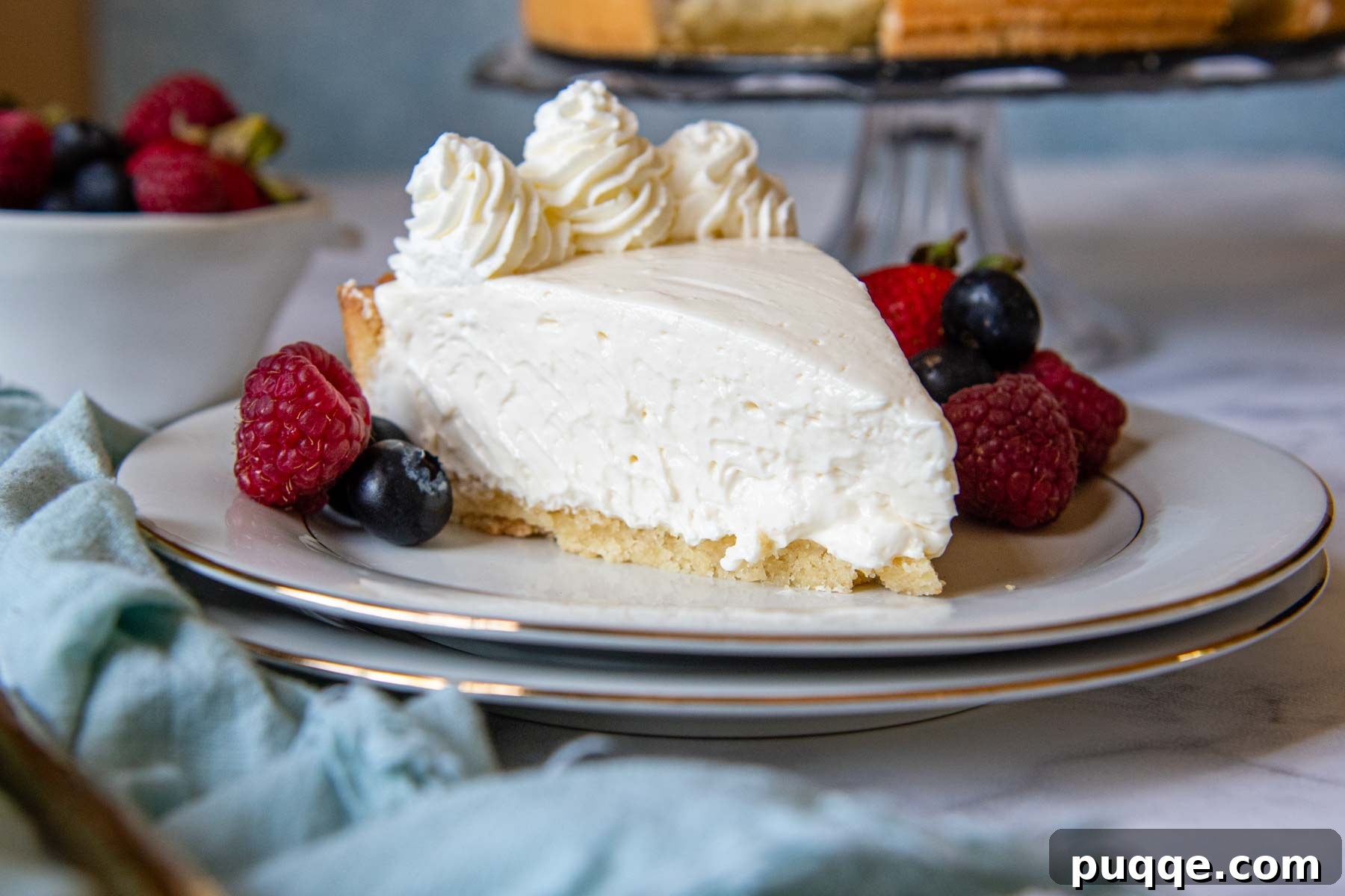 Quick Dreamy Gluten Free No Bake Cheesecake 8 A beautiful slice of gluten-free cheesecake on a white plate, garnished with a vibrant medley of fresh berries, ready to be enjoyed.
