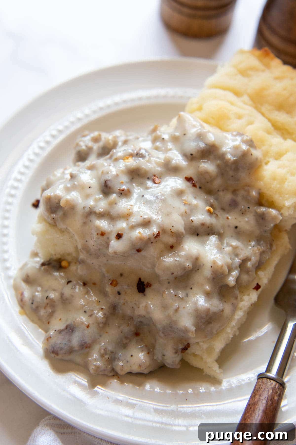Effortless 10-Minute Gluten-Free Sausage Gravy 7 Gluten-free sausage gravy generously poured over two fluffy gluten-free biscuits on a white plate, ready to be enjoyed.