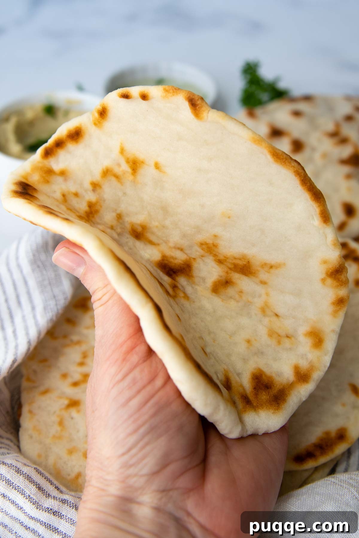 A soft and fluffy gluten-free flatbread being gently folded, highlighting its flexibility and perfect texture.