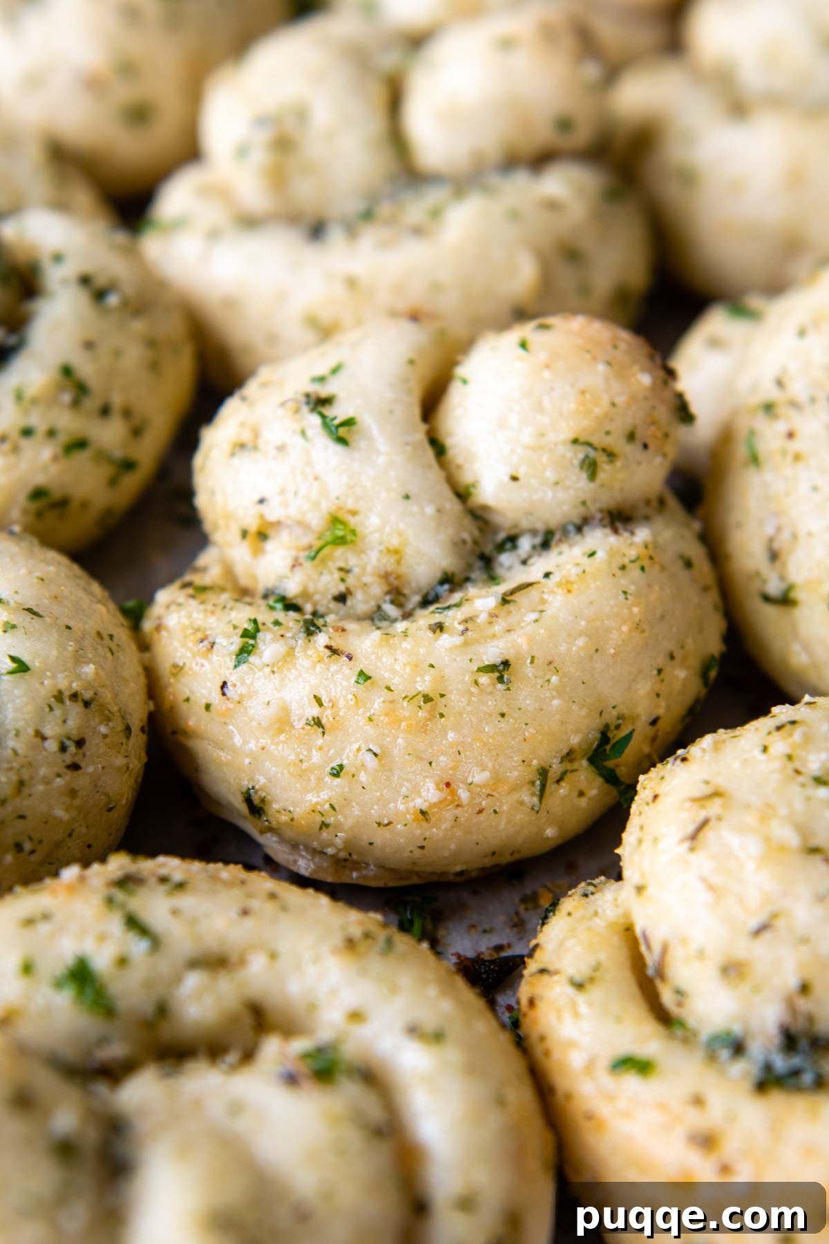 A close-up of a perfectly baked gluten-free garlic knot, glistening with brushed garlic butter.