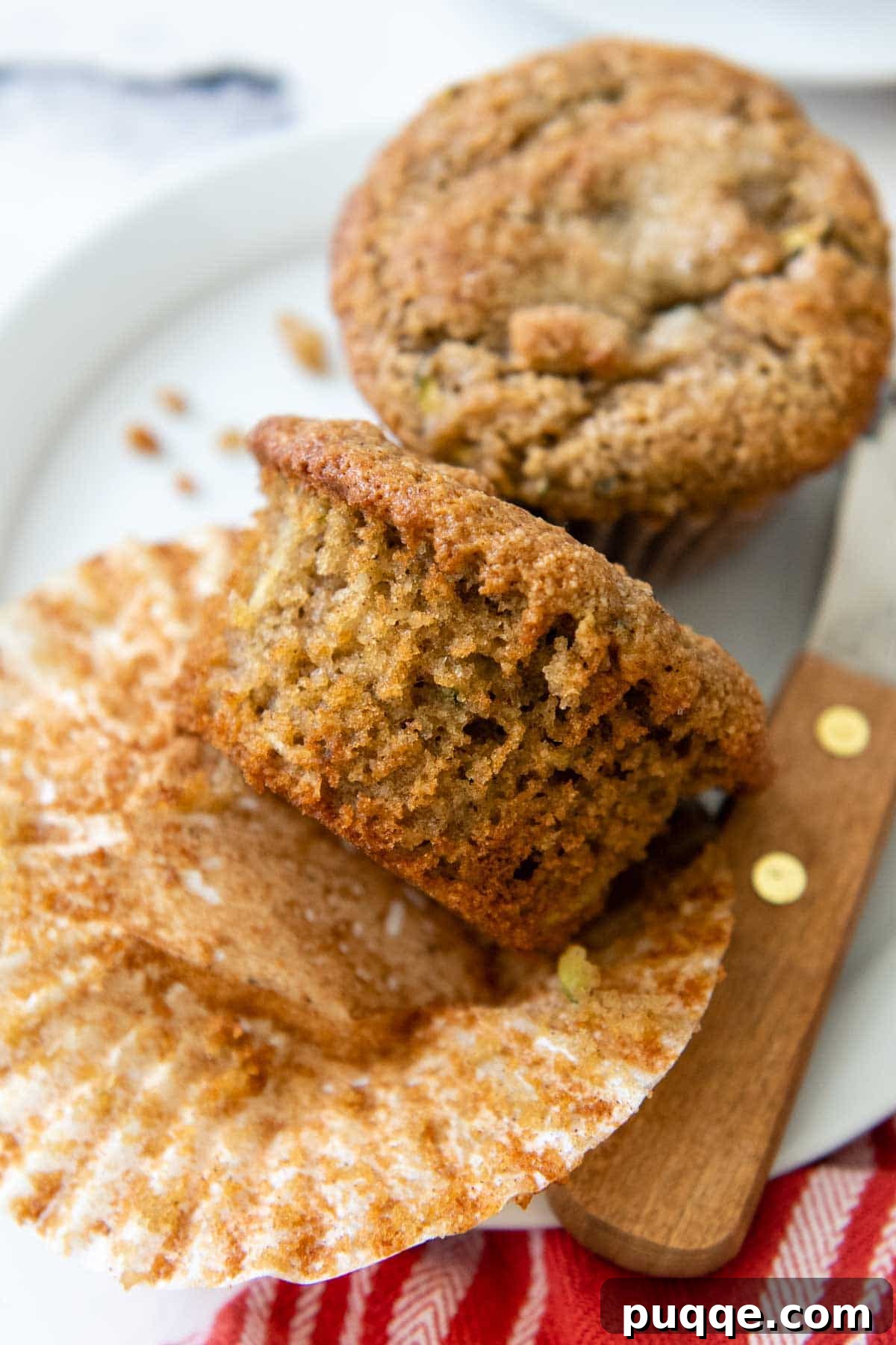 An almond flour zucchini muffin with the paper wrapper removed, showing its fluffy texture.