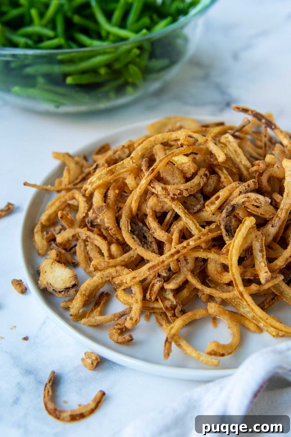65 Must-Try Sides to Elevate Your Pulled Pork 11 a plate of fried onions with a bowl of green beans behind it