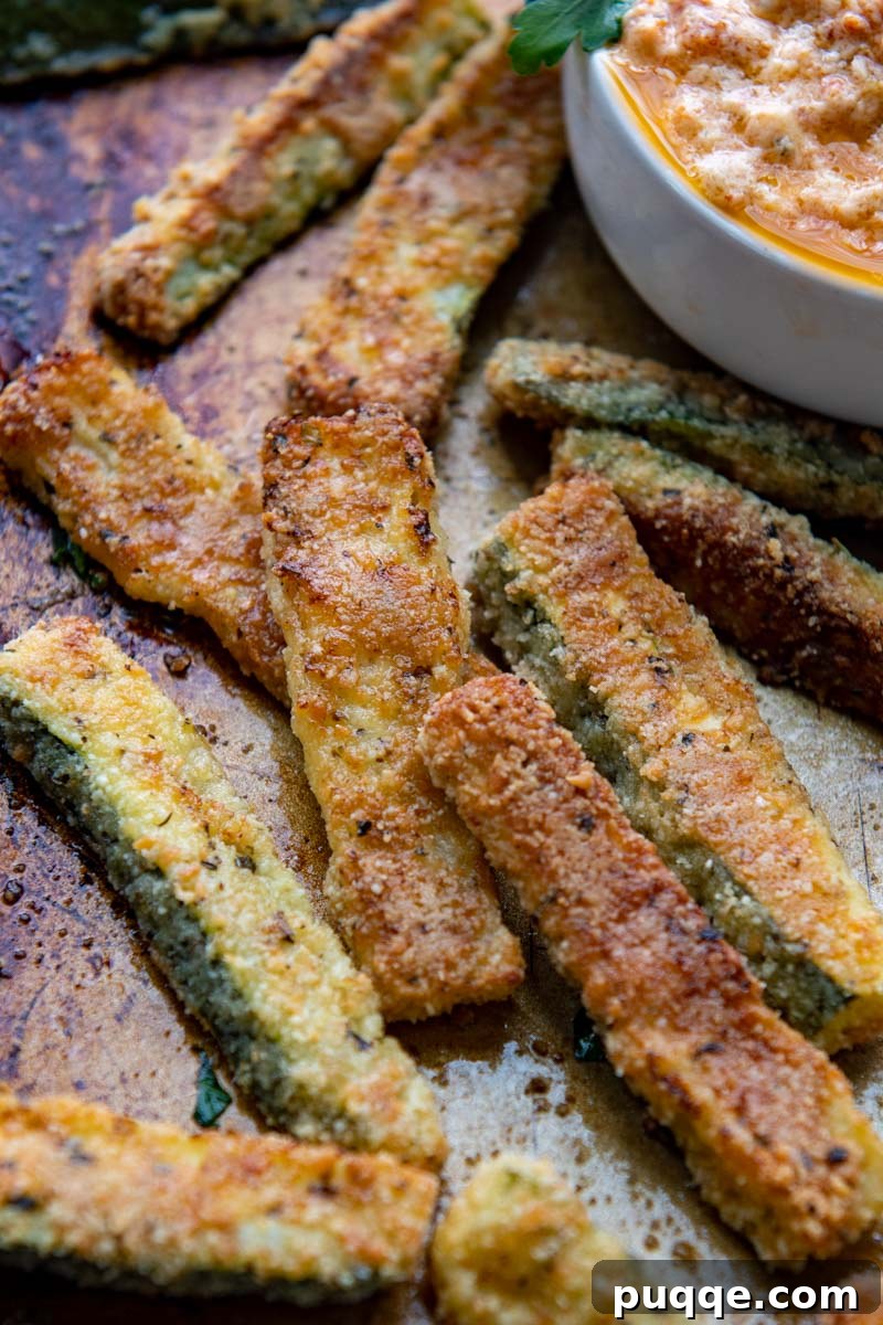 65 Must-Try Sides to Elevate Your Pulled Pork 5 close up of baked zucchini fries on a baking sheet with dip in background