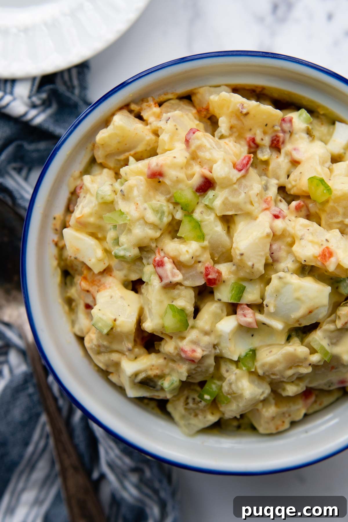 65 Must-Try Sides to Elevate Your Pulled Pork 10 overhead shot of potato salad in a white bowl with a blue linen next to it.
