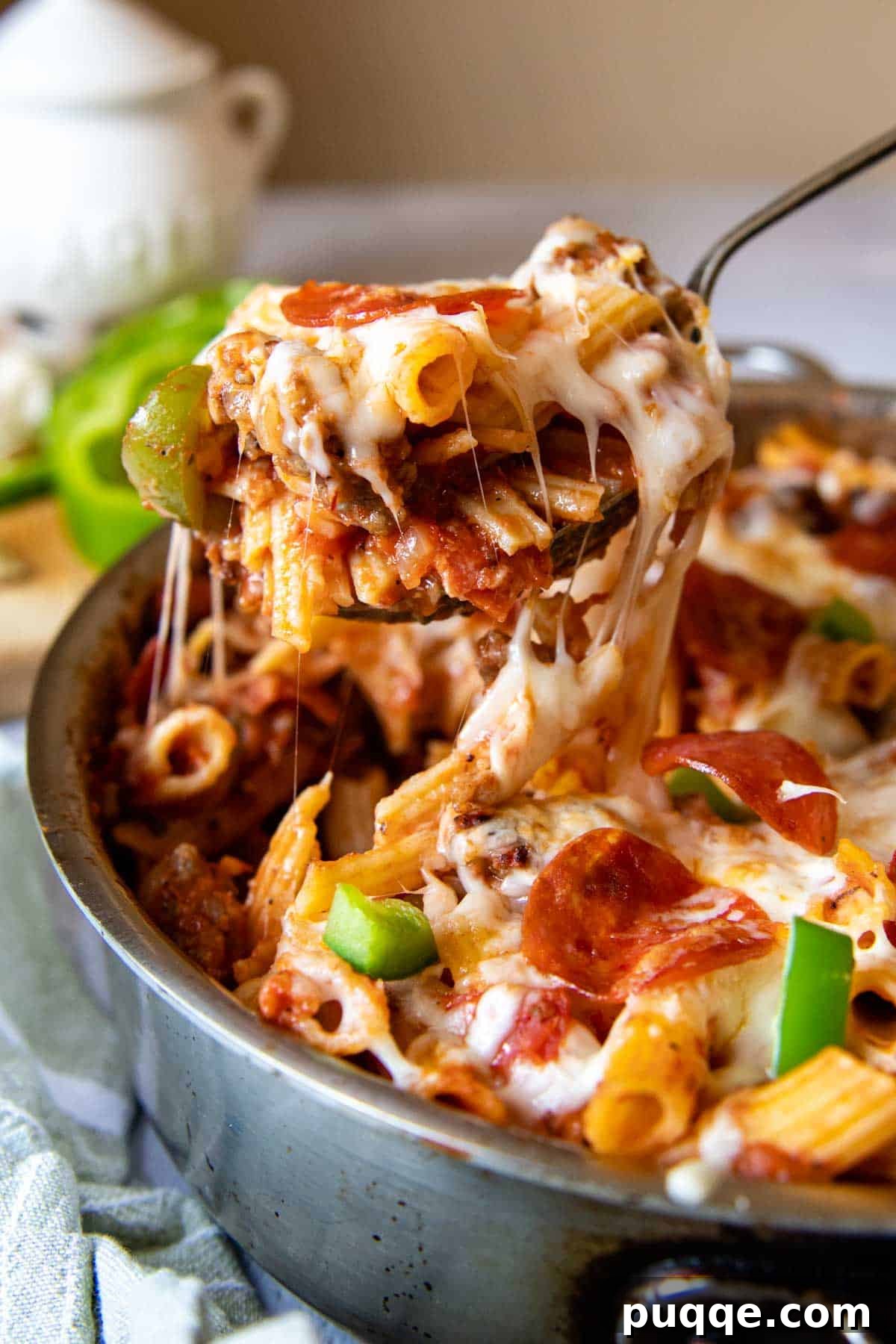 Speedy Supreme Skillet Pizza Pasta 5 A serving spoon lifting a generous portion of cheesy, saucy pizza pasta from the skillet, showcasing the melted cheese and delicious toppings.