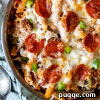 Close-up of baked pasta skillet with a spoon and linen laying next to it.