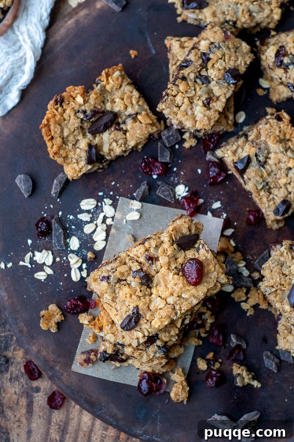 Ultimate Chewy Gluten-Free Chocolate Chip Granola Bars 7 Overhead shot of gluten-free granola bars in a pan, surrounded by various ingredients like chocolate chips, nuts, and oats.