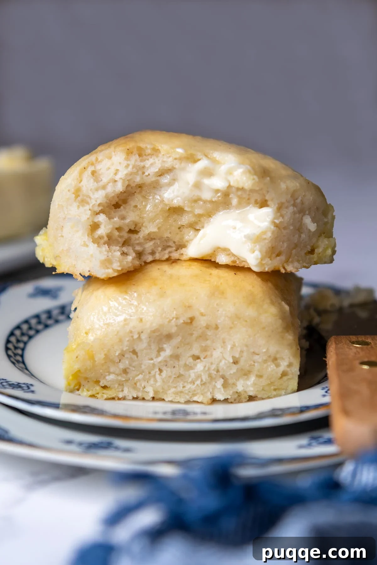 A perfectly baked gluten-free roll, torn open to reveal its soft interior, with melted butter seeping in.