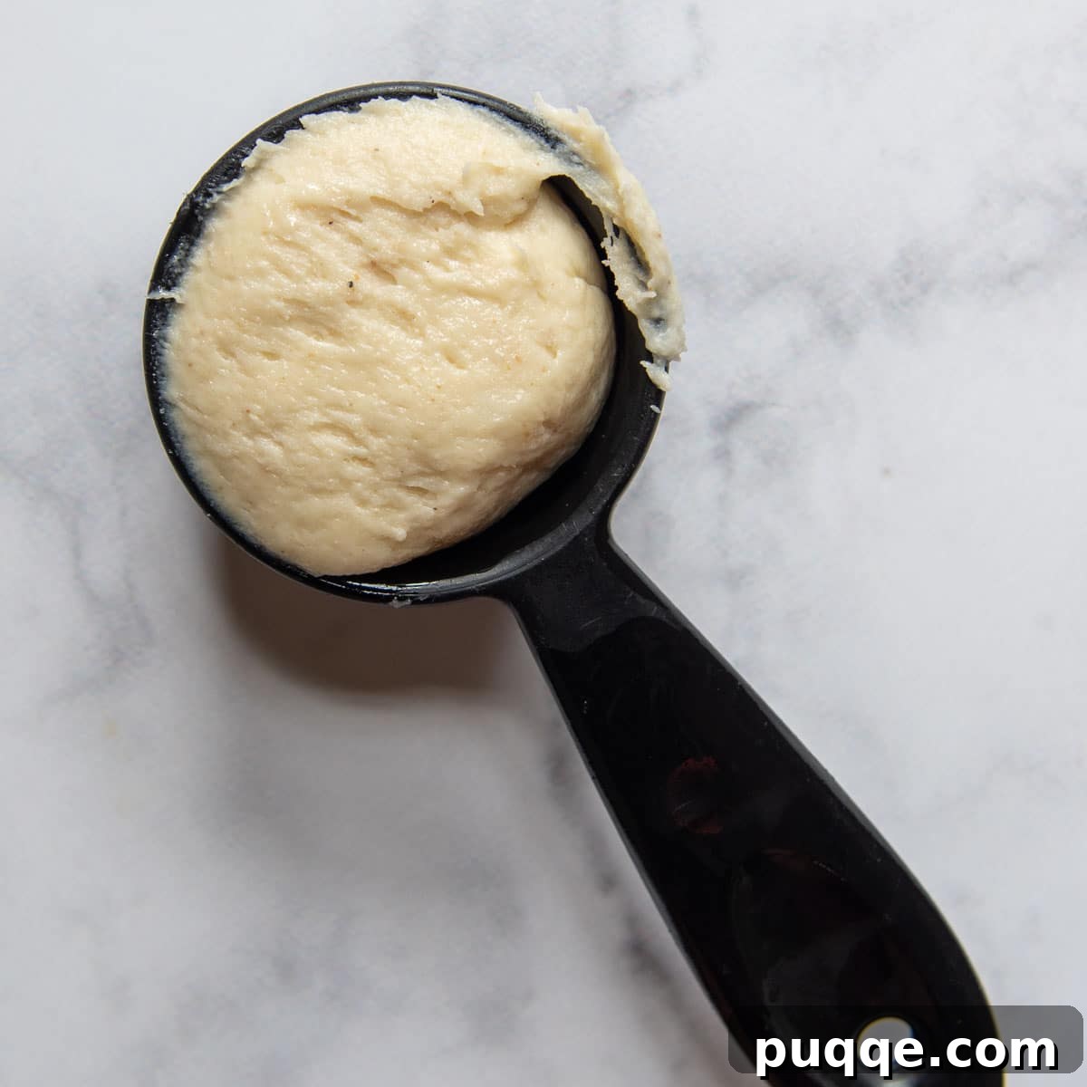 A measuring cup filled with the gluten-free roll dough, demonstrating the simple shaping method.