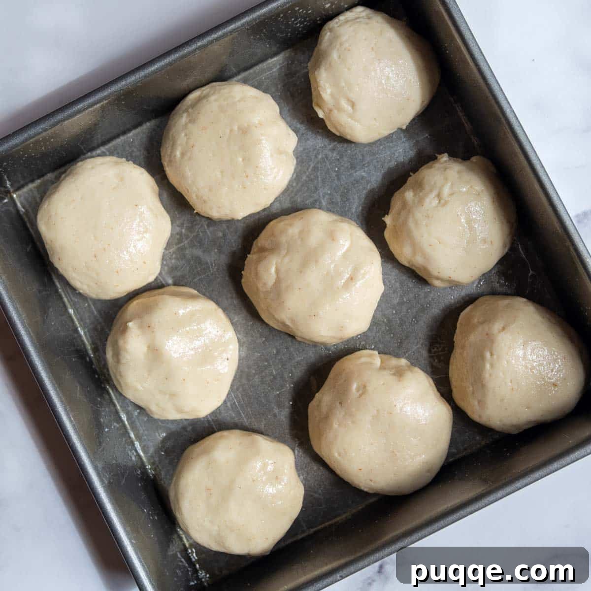 Unbaked gluten-free dinner rolls arranged in a pan before their first rise, looking smooth and ready.