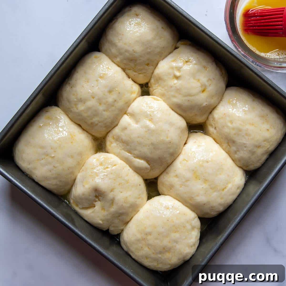 Unbaked gluten-free dinner rolls in a pan after rising, visibly puffier and ready for the oven.