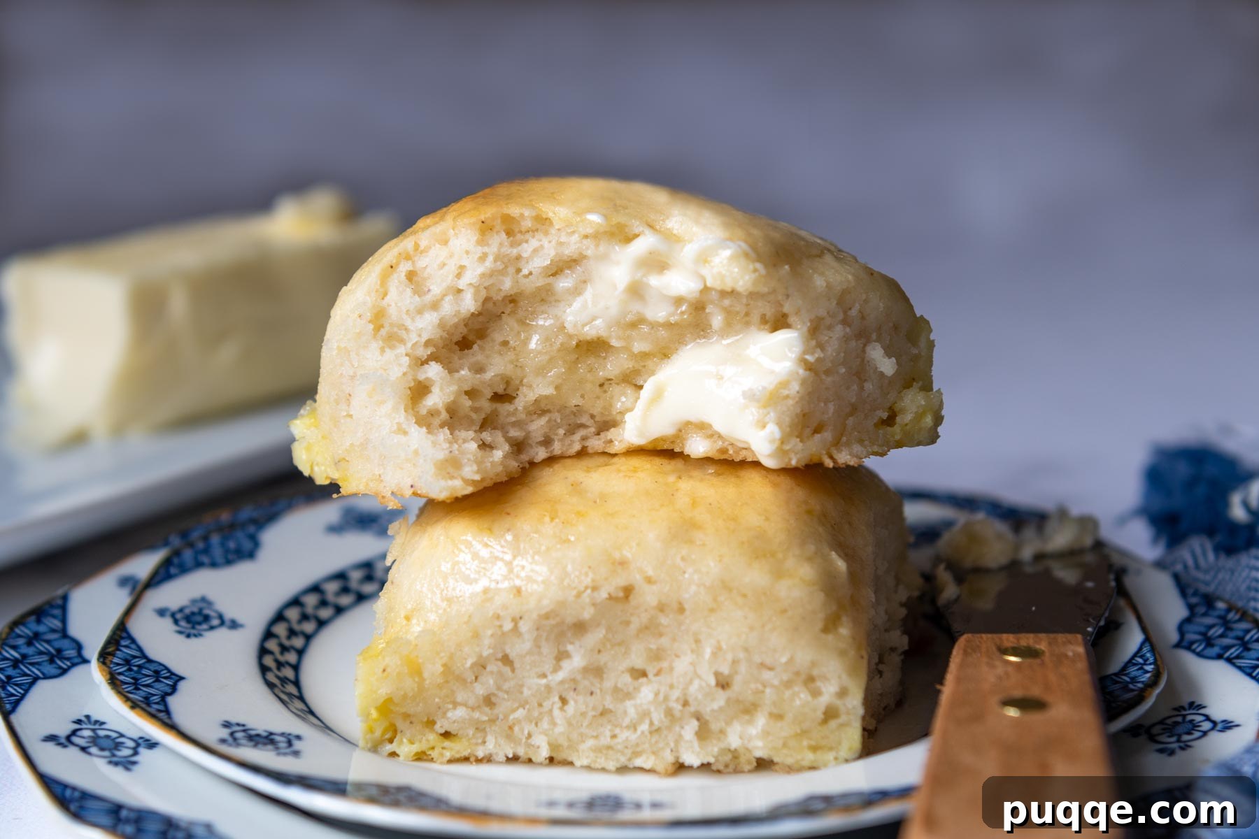 Two soft gluten-free rolls stacked on top of each other, glistening with melted butter.