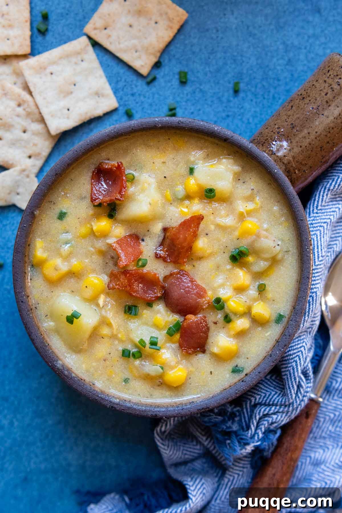 overhead shot of gluten-free corn chowder with crackers and chives scattered around.