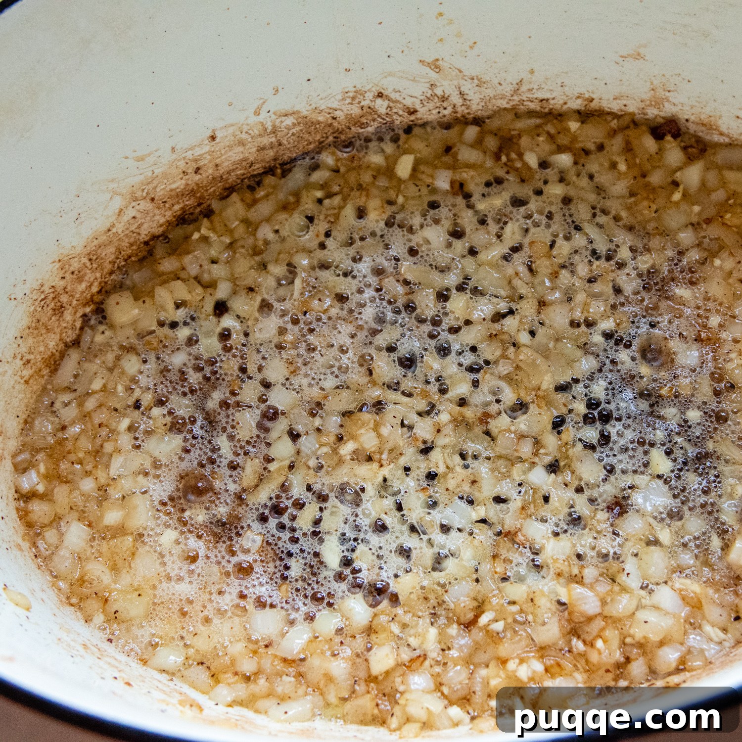 Diced onions cooking in bacon grease and butter until soft and translucent.