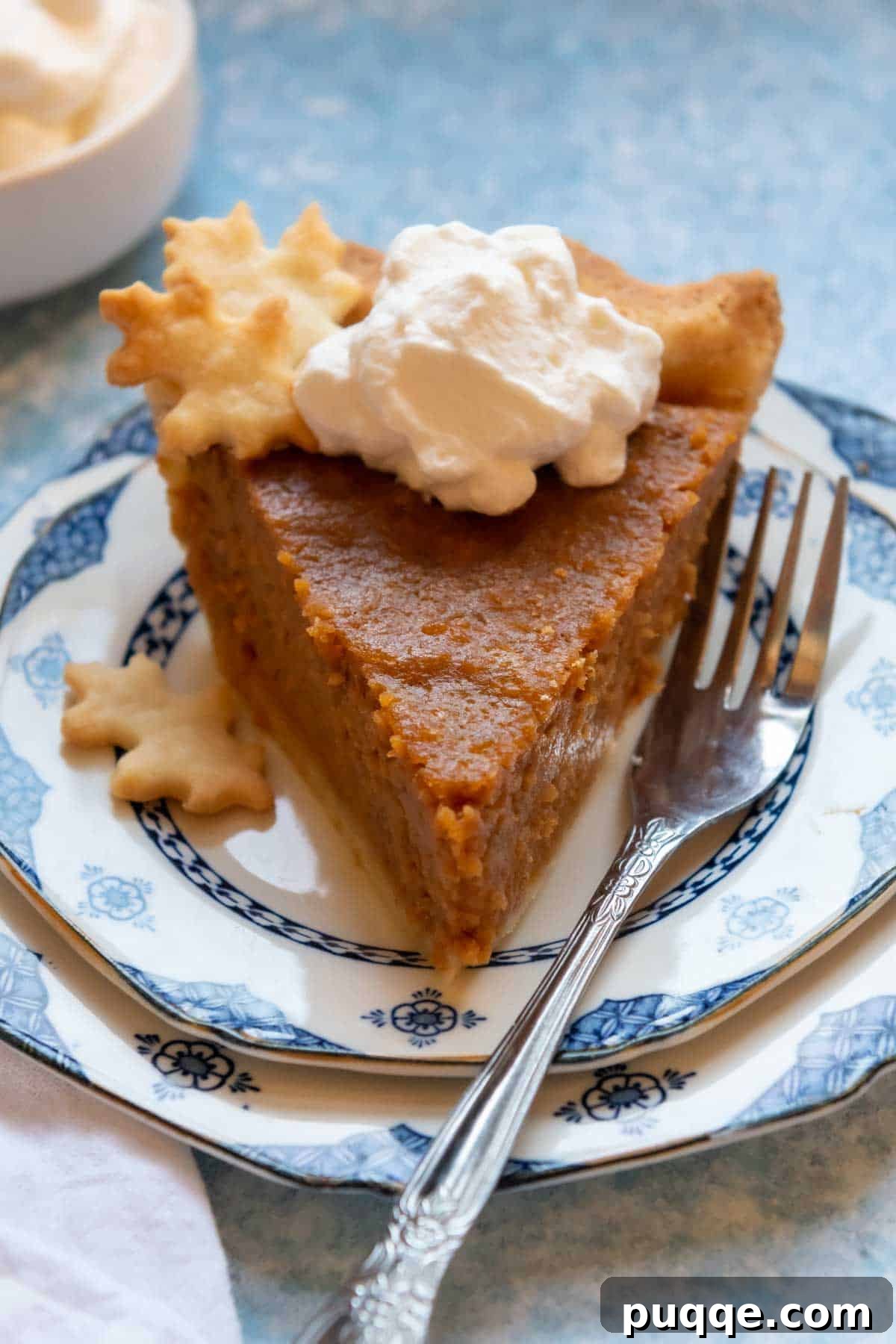 Southern Soul Gluten-Free Sweet Potato Pie with a Flaky Golden Crust 3 a slice of GF sweet potato pie on a blue and white plate with a fork nearby.